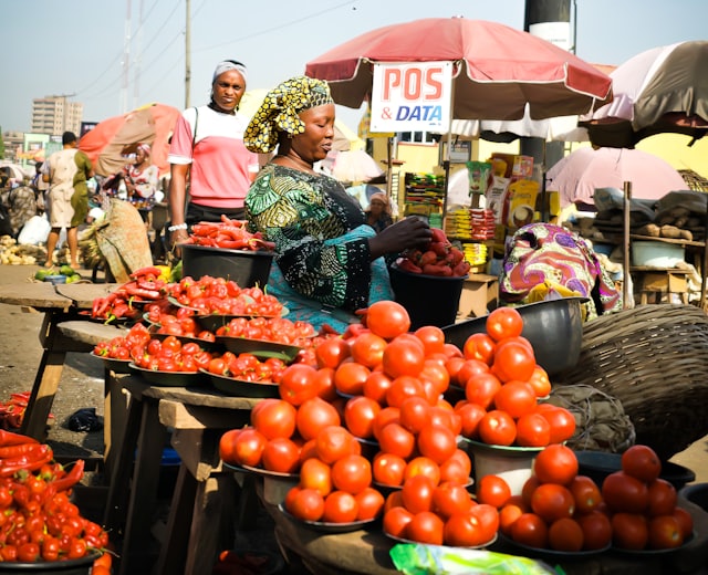 Trader selling fresh produce at a busy market stall