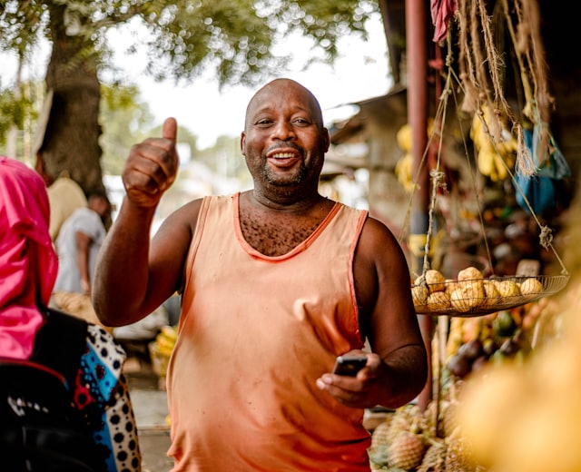 Confident vendor holding a phone at their stall